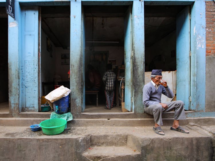 Nepal Elderly Man Sitting On Steps And Drinking