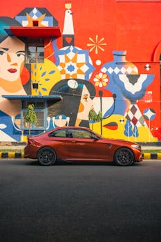 A luxury sports car parked against a vibrant street mural, showcasing urban art and automotive excellence.