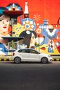 White Sedan Parked Beside Wall With Graffiti