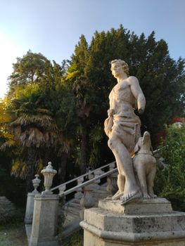 A Renaissance statue near a staircase in a lush garden in Veneto, Italy, capturing the golden hour glow.