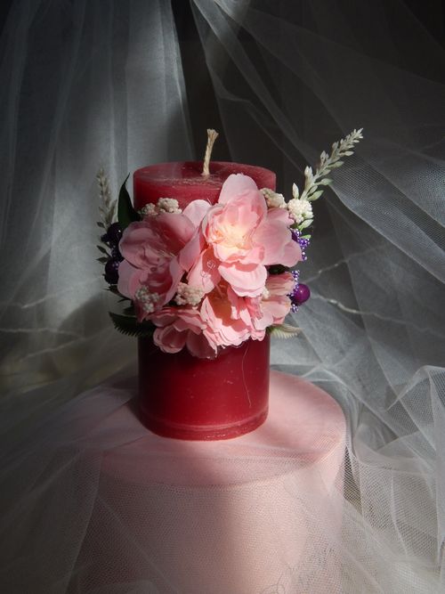 Free Red candle adorned with pink flowers and greenery, creating a romantic ambiance. Stock Photo