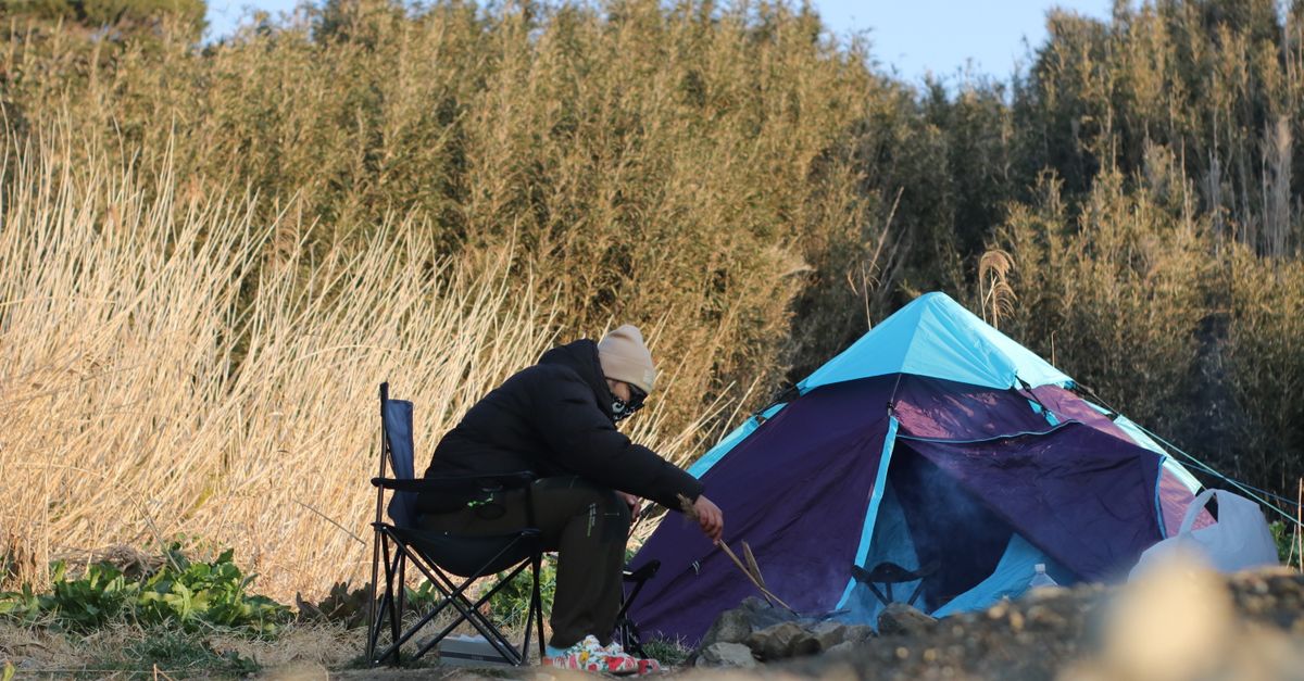 A person enjoys a peaceful camping scene with a colorful tent in the tranquil outdoors of Kanagawa, Japan.
