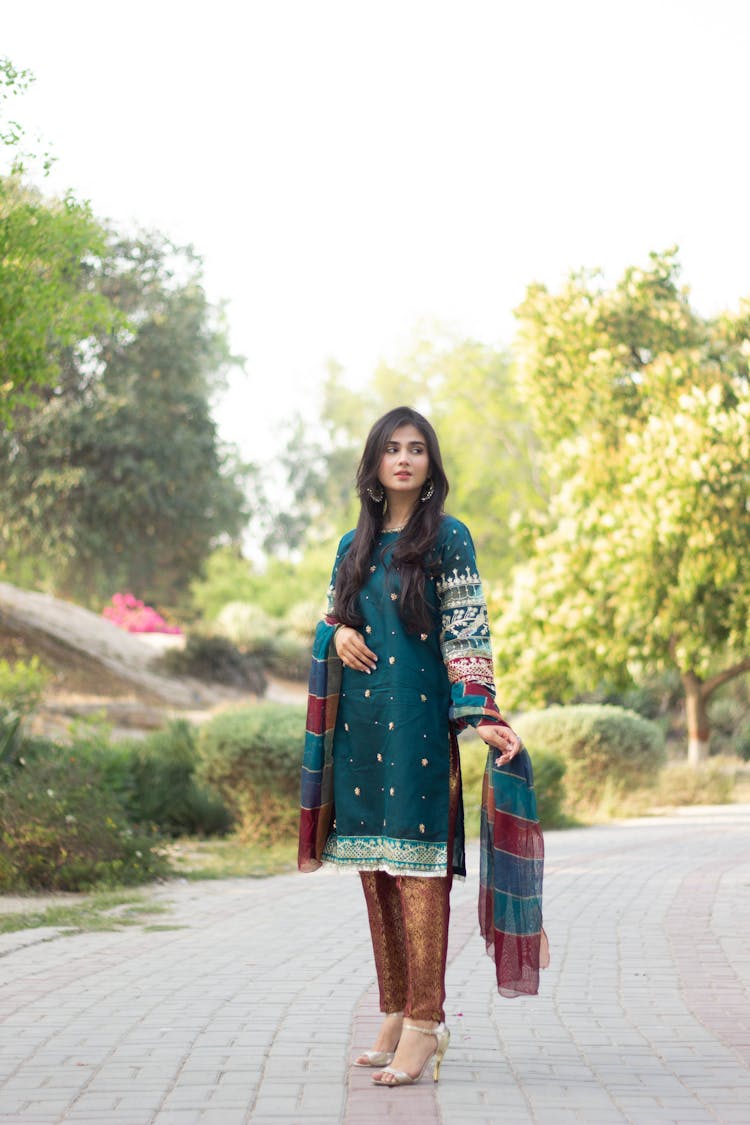 Woman In Traditional Malay Clothes Standing On A Paved Walkway