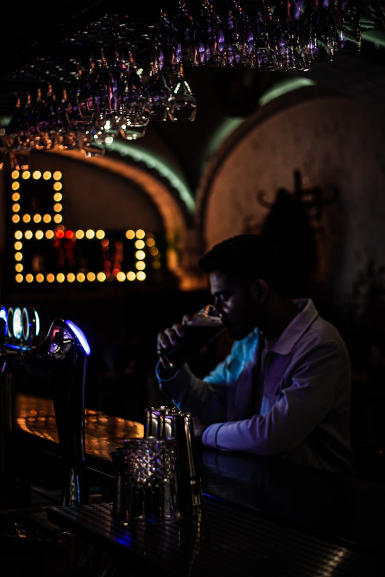 Man In White Dress Shirt Drinking Beer In A Bar