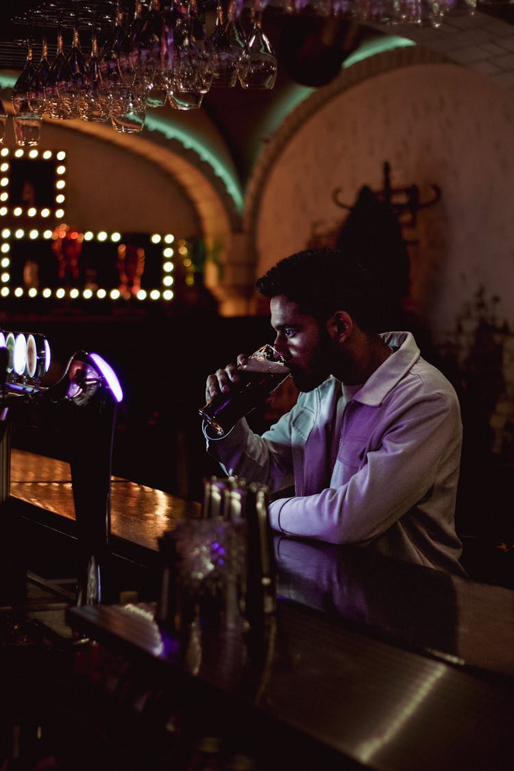 Man Drinking Beer While Sitting At Bar