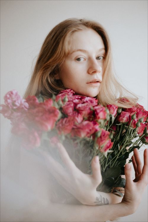 Free A serene portrait of a woman holding a bouquet of pink roses indoors. Stock Photo