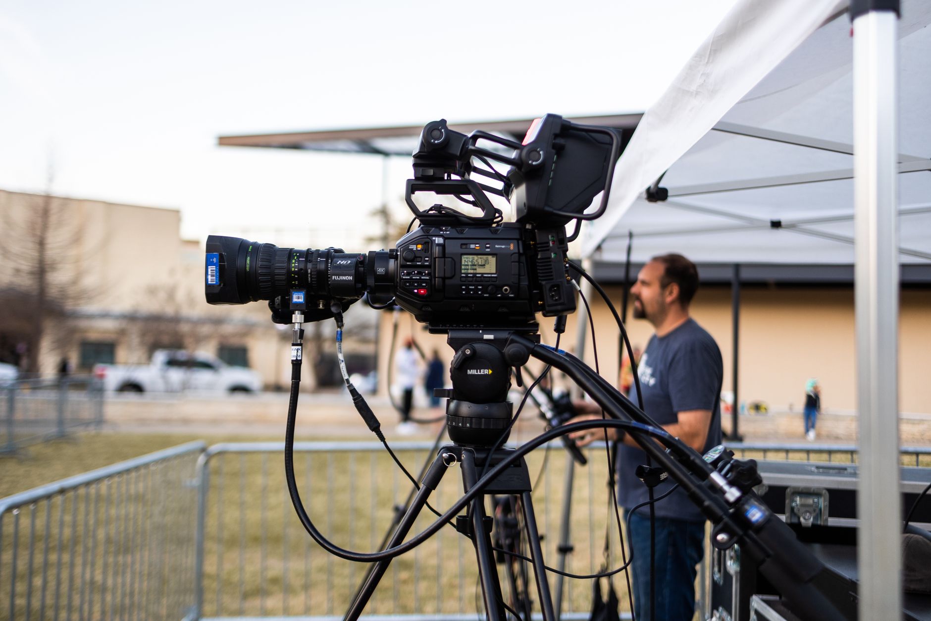 Close view of a professional video camera on a rig with a tripod setup outdoors during daytime.