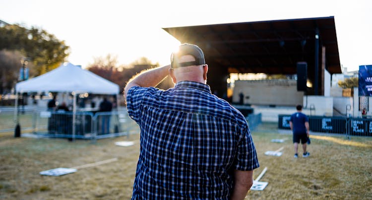 Man In Blue Plaid Top Standing In A Concert Grounds