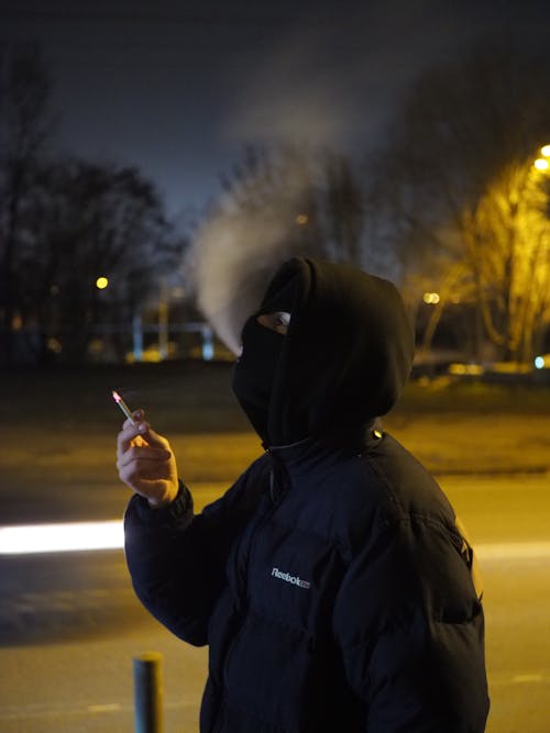 A Person in Black Hoodie Jacket Smoking Cigarette