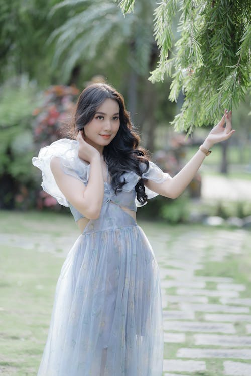 Beautiful Woman in a Dress Holding Tree Leaves