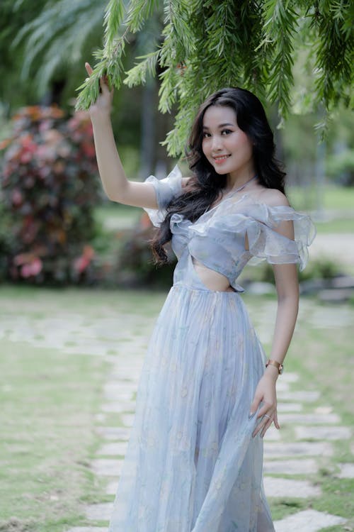 Beautiful Woman in a Dress Holding Tree Leaves