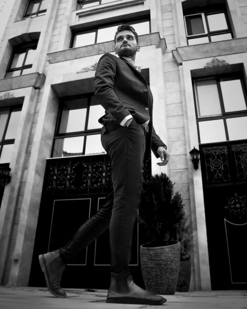 Free Low angle shot of a man in a suit walking confidently in an urban setting. Stock Photo