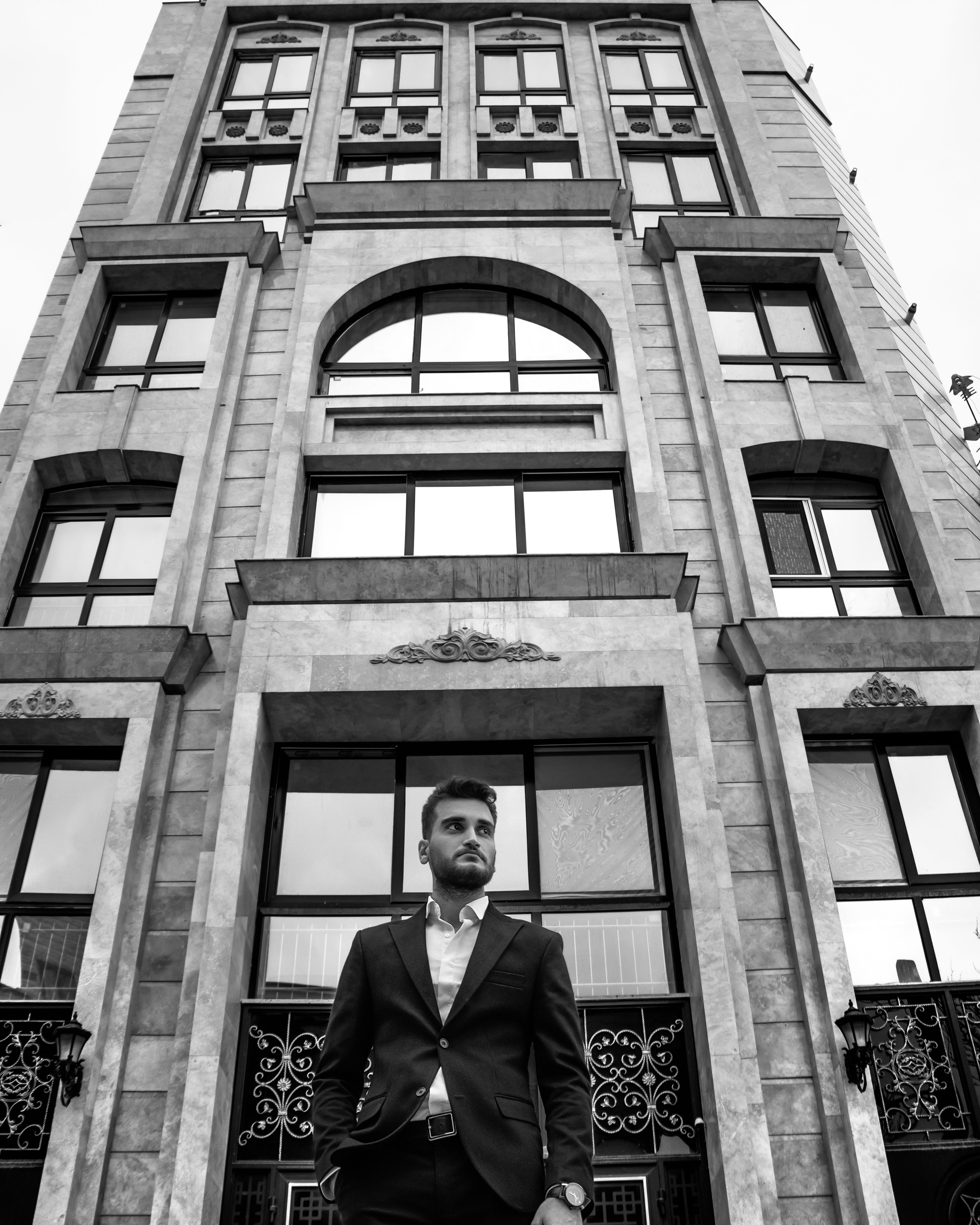 Low angle shot of a man in front of a tall building, showcasing architecture.