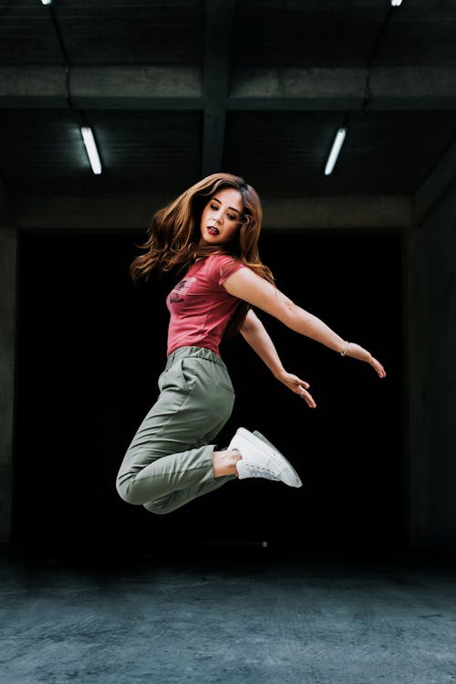 Woman in Red Shirt and Green Jogging Pants Jumping