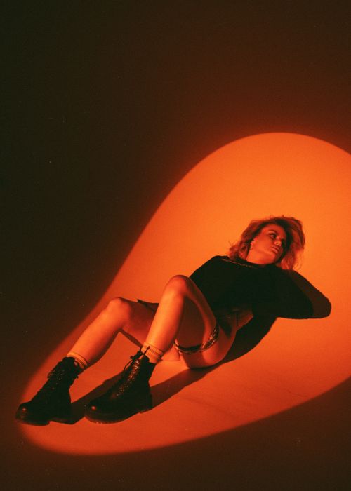 Free A woman model in black boots poses artistically under a warm spotlight. Stock Photo