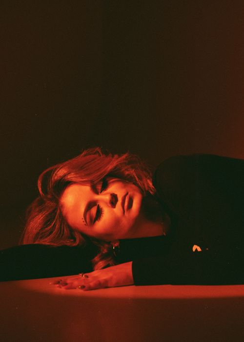 Free Captivating image of a woman lying down with eyes closed, enveloped in warm red light. Stock Photo
