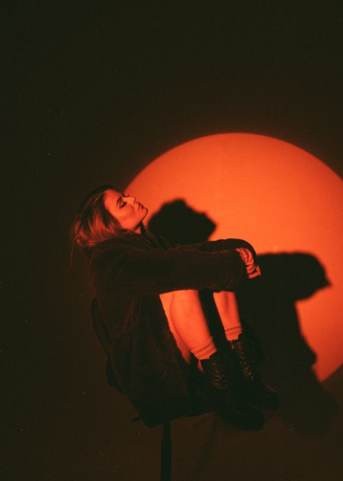 Free Dramatic studio portrait of a woman in red light with striking shadows. Stock Photo
