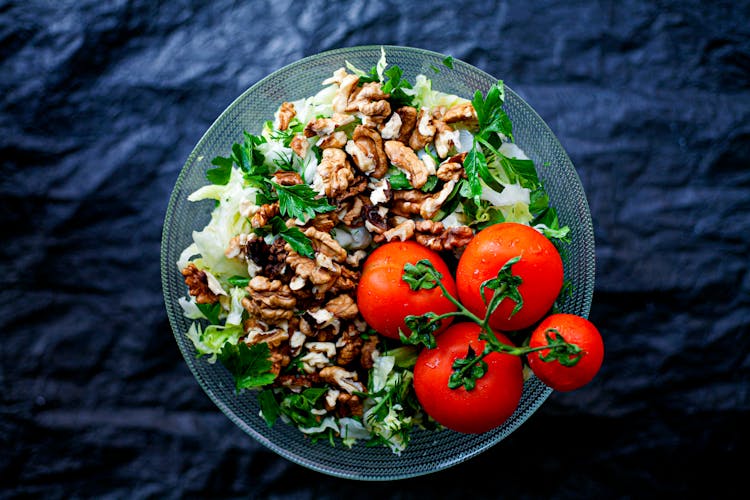 Red Tomatoes On Mixed Vegetables Salad And Nuts In A Glass Bowl 