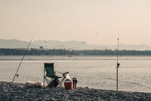 Tranquil pebble beach with fishing rods and chair, perfect for a calm day by the sea.