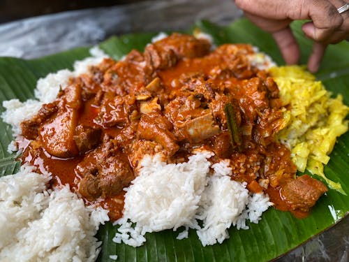 Cooked Food and Rice Served on Banana Leaf