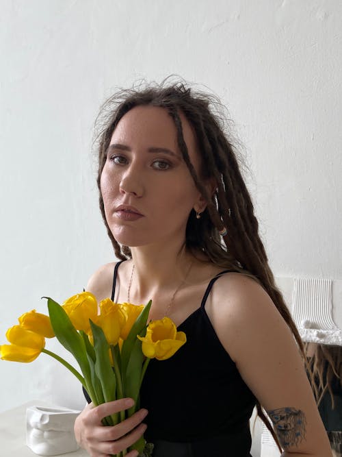 A Woman in Black Tank Top Holding a Yellow Flowers