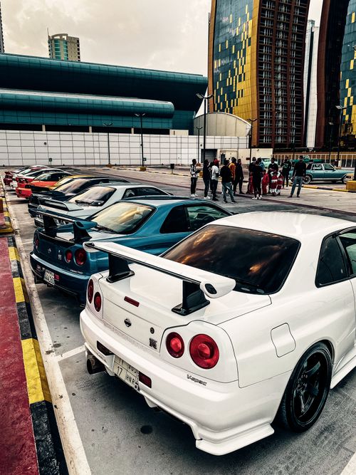 Free Aerial view of a diverse group enjoying a car meet in a city parking area with sports cars. Stock Photo