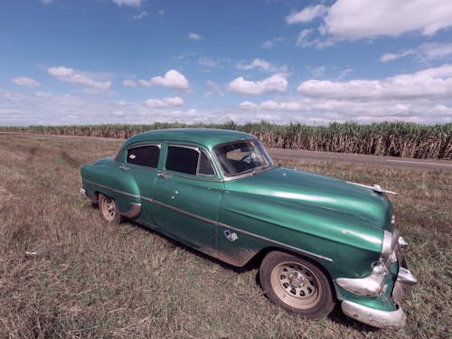 A Green Vintage Car Parked on Brown Grass Field