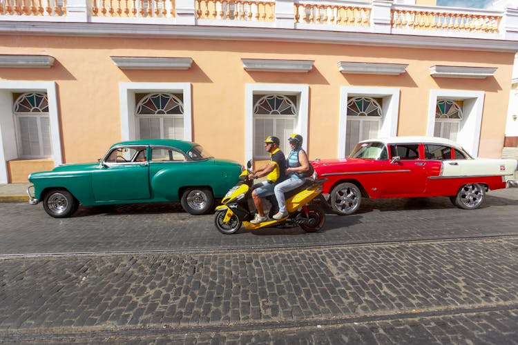 A Couple Riding A Scooter