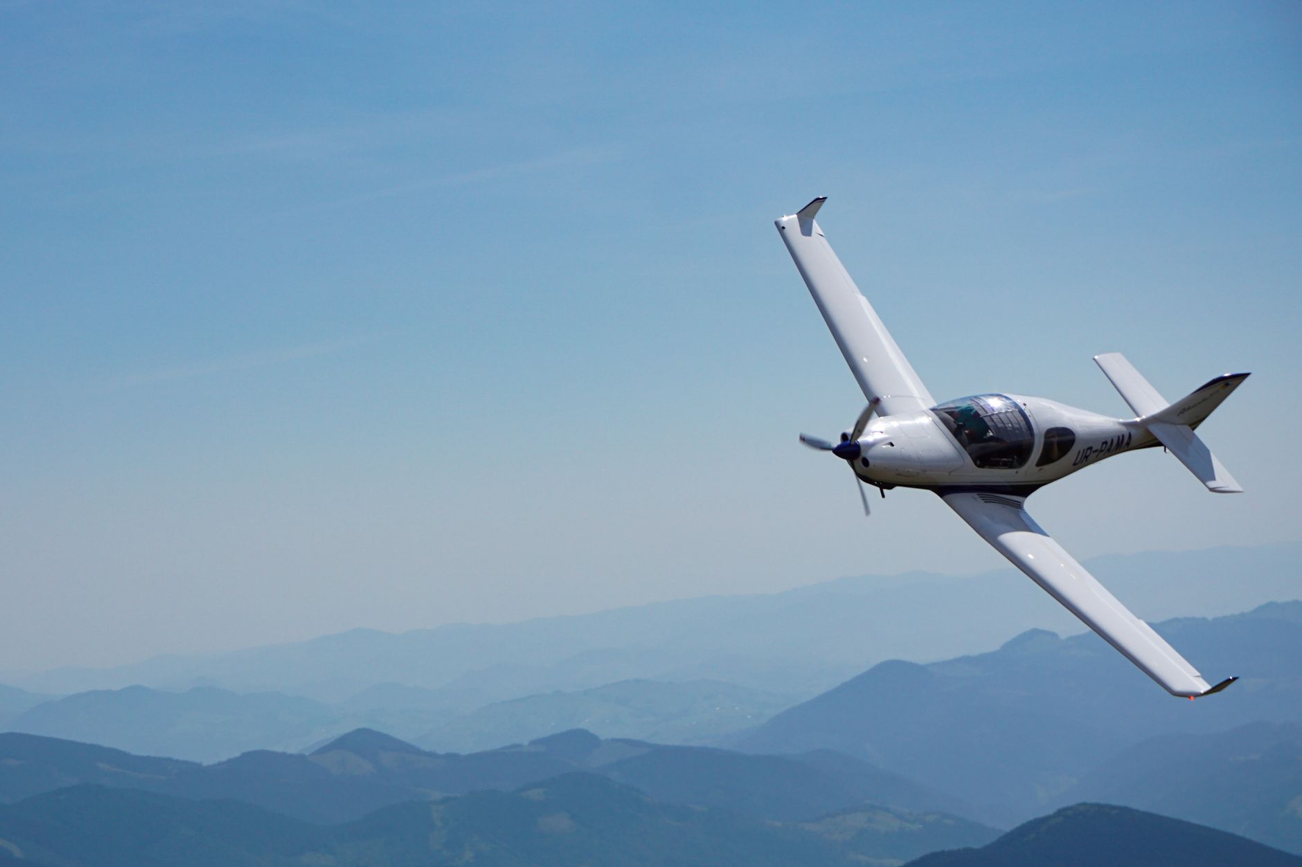 A sleek light aircraft soaring over the scenic mountains in Zakarpattia Oblast, Ukraine.