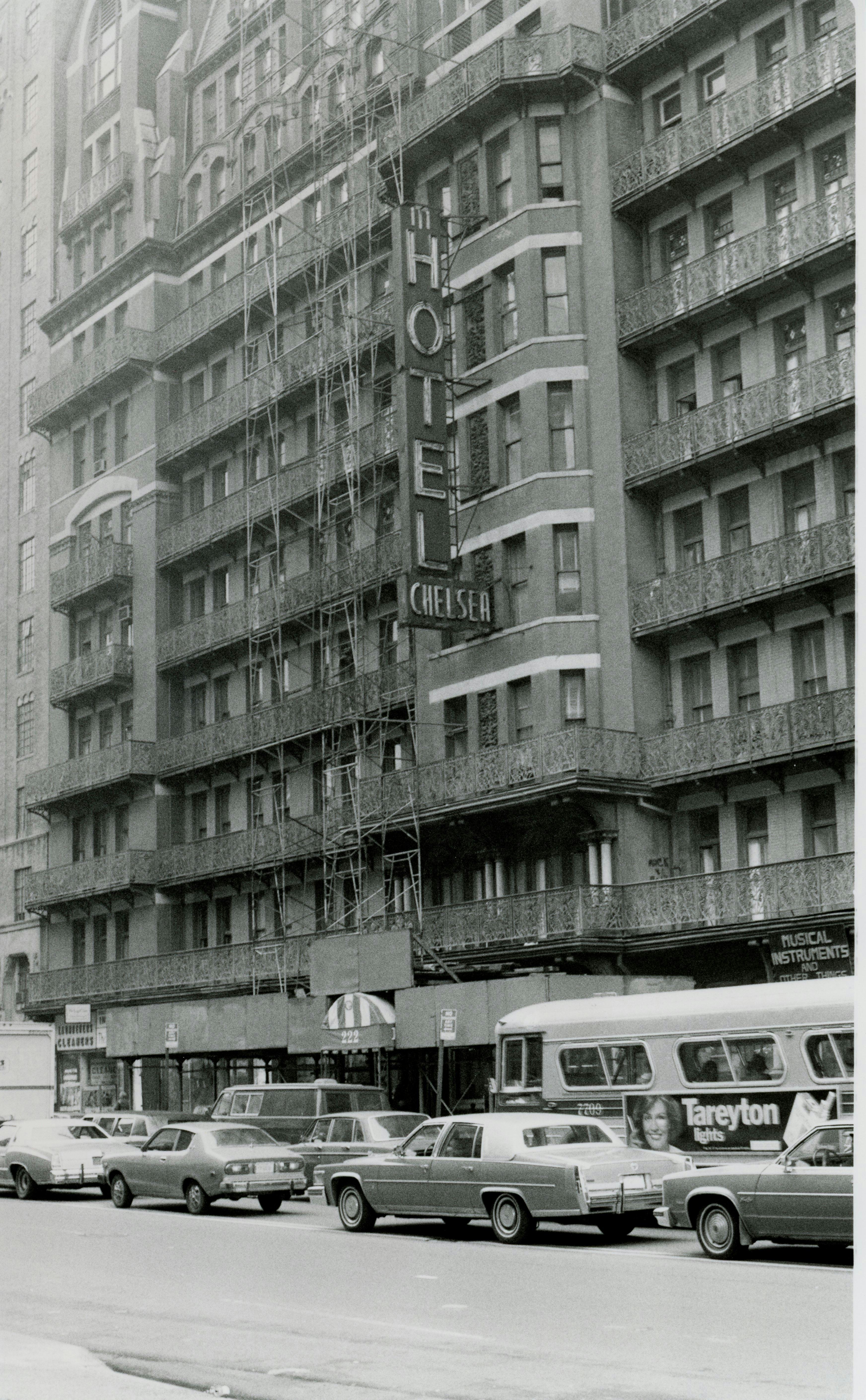 Black and white image of Hotel Chelsea exterior with 1970s cars on NYC street.