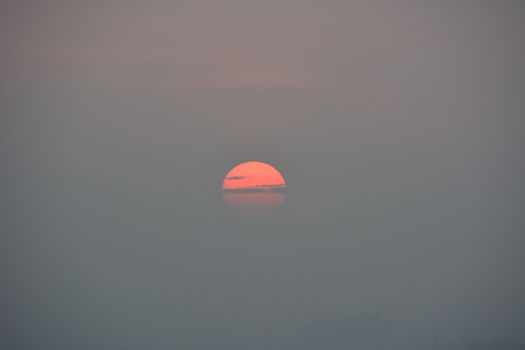 Beautiful sunset peeking through misty clouds, creating a tranquil and moody atmosphere.