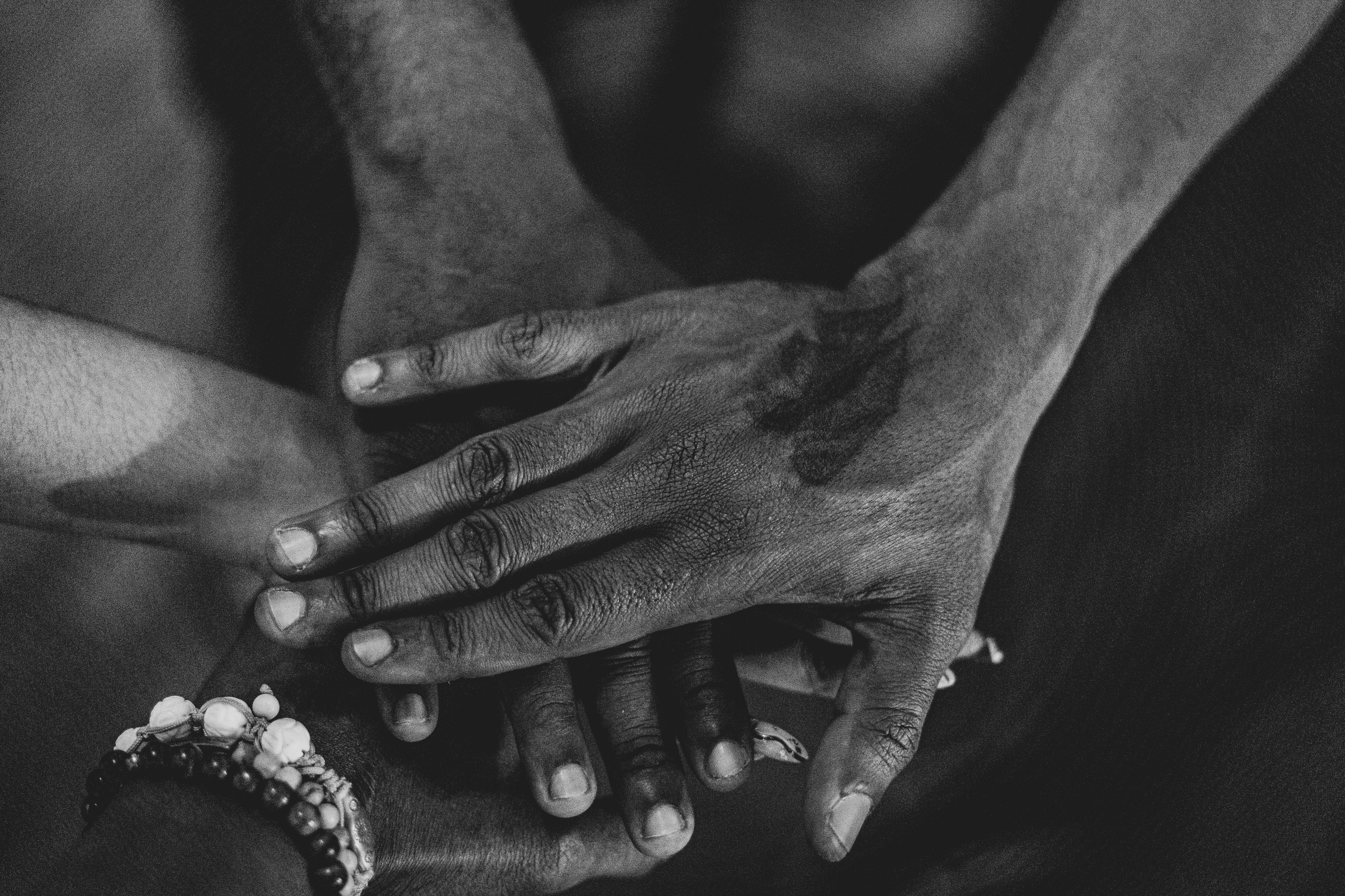 grayscale photo of people s hands stacked together