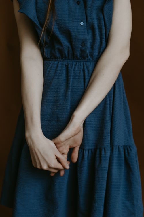 Free Close-up of a woman in a blue dress, hands clasped gracefully in front. Stock Photo