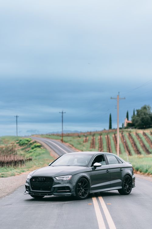 Free Sleek gray Audi S3 parked on a rural road with vineyard backdrop. Stock Photo