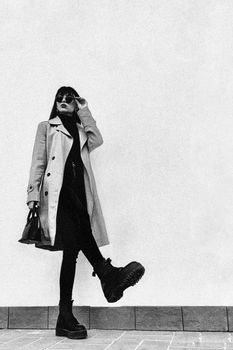 Fashionable woman in trench coat and boots striking a pose at Oleggio, Italy.