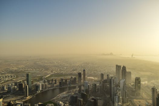 A breathtaking aerial view of a sprawling modern cityscape at sunrise with prominent skyscrapers and calm ambiance.
