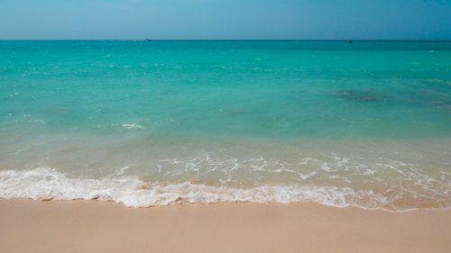 Free Serene beach scene with turquoise waves and sandy shore, perfect for relaxation imagery. Stock Photo
