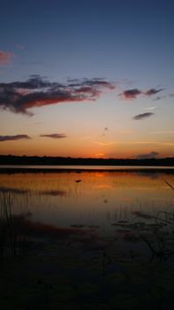 Beautiful sunset reflecting on tranquil lake with peaceful colors and sky.