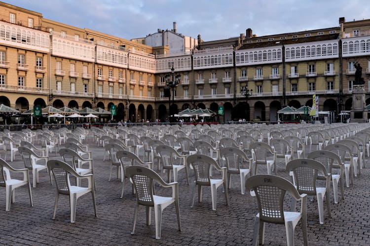 White Plastic Chairs In A Courtyard 