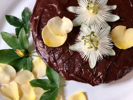 A chocolate cake adorned with passionflowers and petals, perfect for food photography.