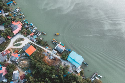 Free Scenic aerial view of a vibrant riverside village with boats docked along the shore. Stock Photo