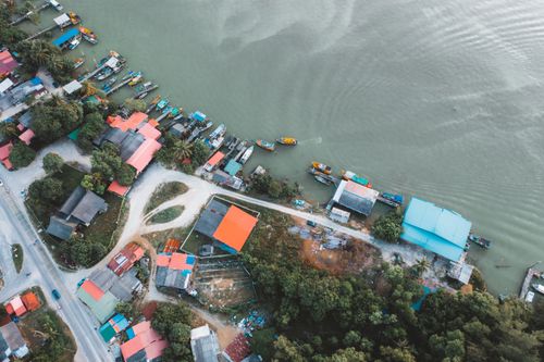 Free A scenic aerial shot captures a vibrant waterfront village with boats docked along the shore. Stock Photo
