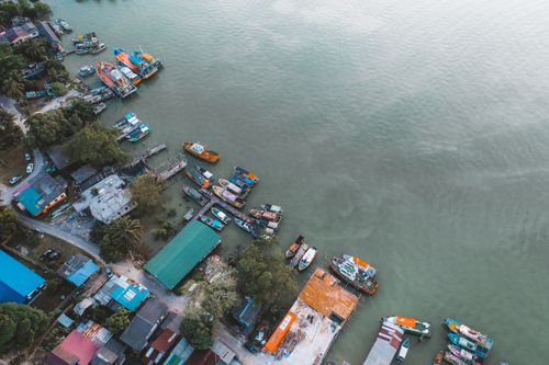 Free Colorful boats docked at a bustling coastal harbor viewed from above. Stock Photo