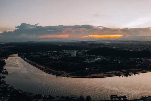 A breathtaking aerial view of a riverfront cityscape at dusk with dramatic skies.