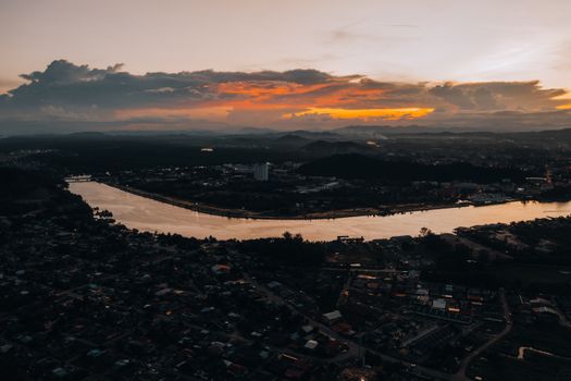 Capture of a serene cityscape at sunset with vibrant clouds and a winding river.