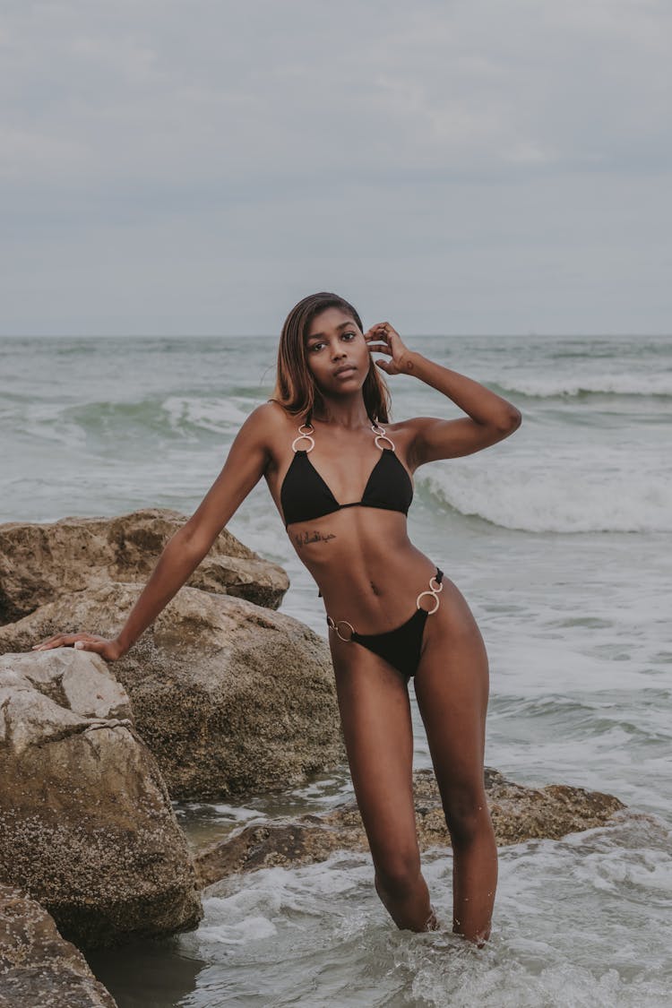 Woman Standing In Shallow Water By Rocks