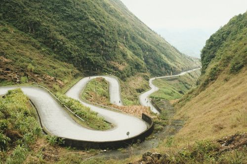 Free Winding road cutting through lush green mountainside offering a serene nature view. Stock Photo