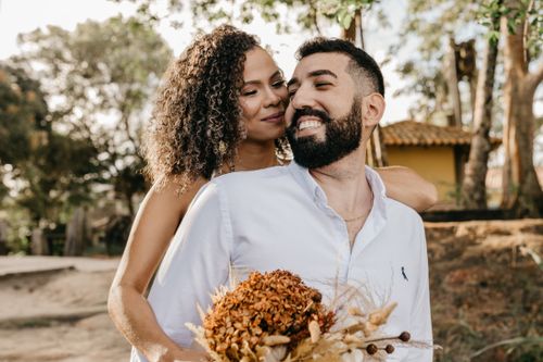 Free Romantic couple embracing outdoors with a dried bouquet, enjoying a sunny day. Stock Photo