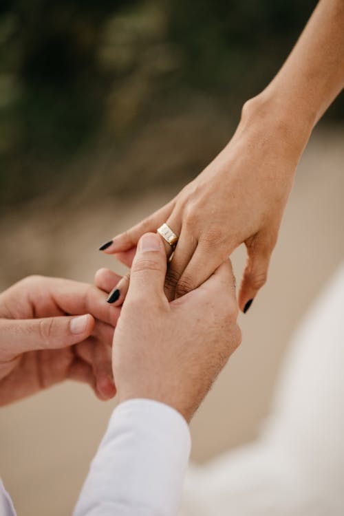 Man Hands Putting Wedding Ring on Woman Finger