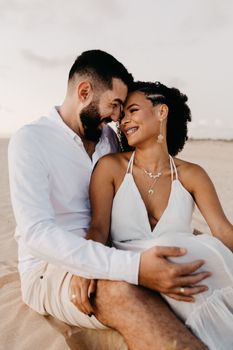 Joyful couple hugging on a beach, radiating love and happiness under a clear sky.